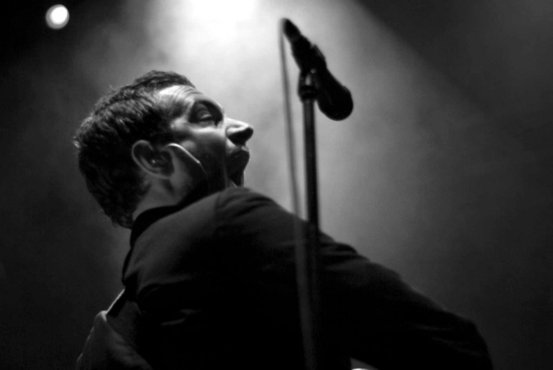The Editors gig photographer Man plays a guitar behind a microphone