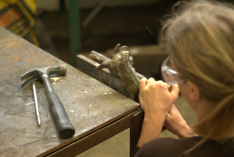 Bronze casting art event at Yorkshire Sculpture Park Woman filing metal at Yorkshire Sculpture Park