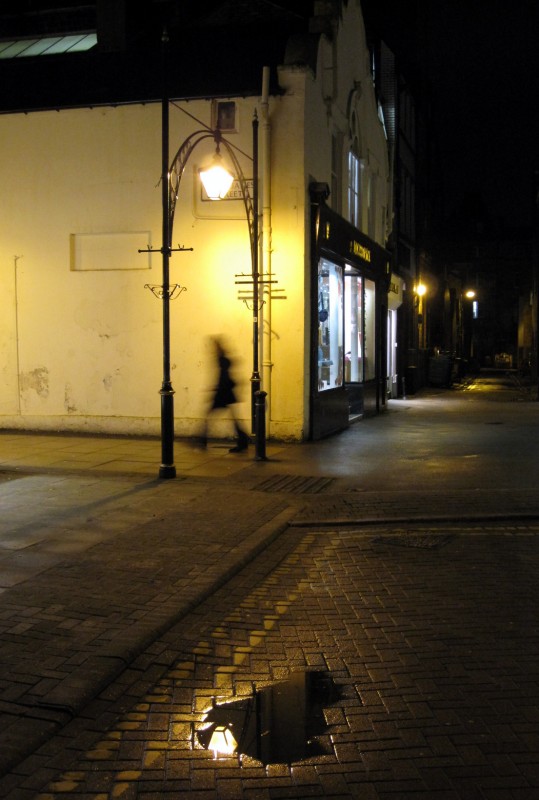 Harrogate street at night A blurred pedestrian walks through a wet Harrogate street at night